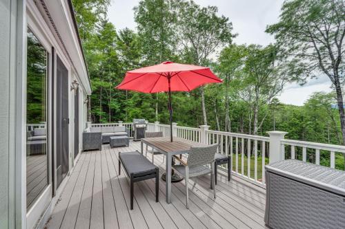a wooden deck with a table and an umbrella at Campton Home with Mountain Views Near Trails and Lake in Campton