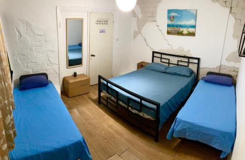 two beds in a room with blue sheets at Dotan's Boutique Guesthouse - By The Beach! in Tel Aviv
