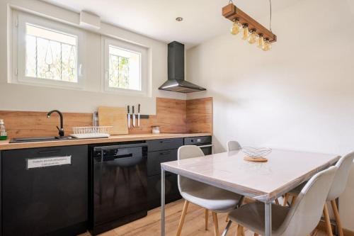 une cuisine avec une table, des chaises et un évier dans l'établissement Meublé de tourisme 3 étoiles avec terrasse et jardin, à Bagnols-sur-Cèze