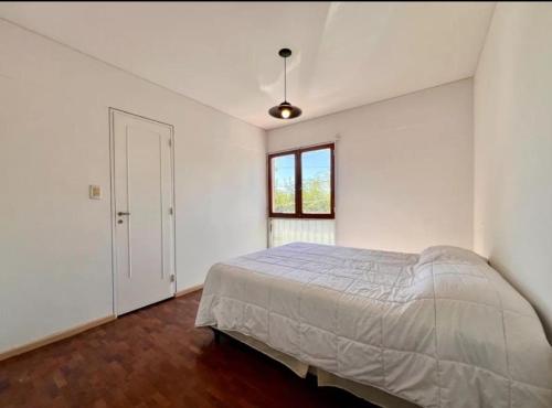 ein weißes Schlafzimmer mit einem Bett und einem Fenster in der Unterkunft Departamento centro Mendoza a Pasos de la terminal in Barraquero