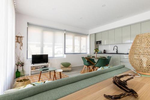 a living room with a green couch and a kitchen at Casa na Areia in Leiria