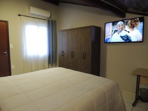 a bedroom with a bed and a flat screen tv at Pousada Cusco - Centro de Jaraguá do Sul in Jaraguá do Sul