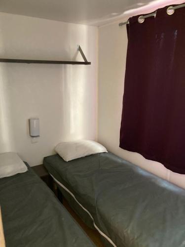Cette petite chambre comprend 2 lits et un rideau. dans l'établissement camping paisible Marvilla park, à Agde