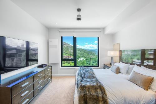 a bedroom with a large bed and large windows at Electric Pass Lodge by Snowmass Vacations in Snowmass Village