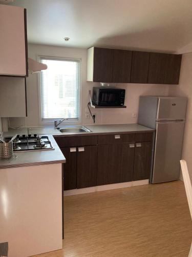 La cuisine est équipée de placards bruns, d'un évier et d'un réfrigérateur. dans l'établissement camping paisible Marvilla park, à Agde