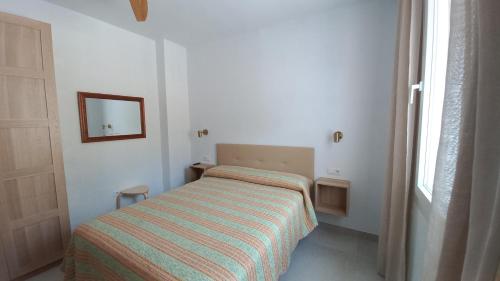 małą sypialnię z łóżkiem i lustrem w obiekcie Casa Cuartel El Delfín w Maladze