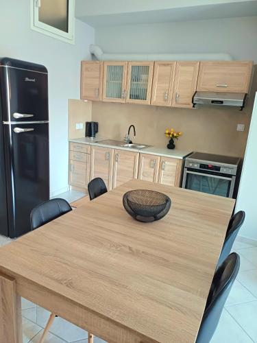 a kitchen with a wooden table and a black refrigerator at Angela's Apartment in Chalkida