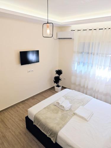 a white bedroom with a large bed with towels on it at New Apartment close to Sea and Downtown in Vlorë