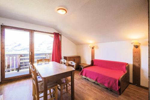 - une chambre avec un lit rouge, une table et une fenêtre dans l'établissement Résidence La Crête du Berger - maeva Home - Appartement 2 pièces 6 personnes - Confort MAE-1754, à Agnières-en-Dévoluy