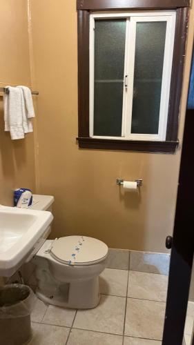 a bathroom with a toilet and a sink and a window at Jumping Frog Motel in Angels Camp