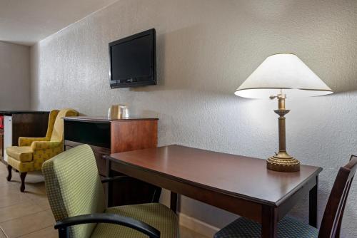 a hotel room with a desk with a lamp and chairs at Rodeway Inn Clermont - Minneola - Groveland - Leeseburg in Clermont