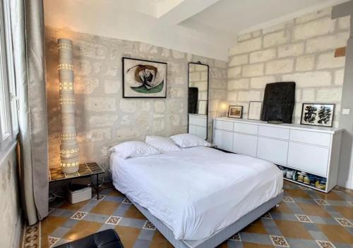 une chambre avec un lit blanc et un mur en pierre dans l'établissement T3 centre historique, 90m2, clim, terrasse, 4 pers, à Avignon