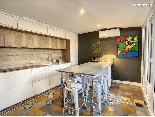 une cuisine avec une table et quelques placards blancs dans l'établissement T3 centre historique, 90m2, clim, terrasse, 4 pers, à Avignon