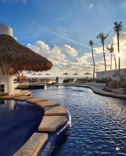 a swimming pool at a resort with palm trees at Depa de lujo en Acapulco diamante con club de playa a pie-Precio especial in Acapulco