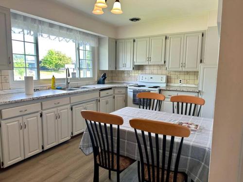eine Küche mit weißen Schränken und einem Tisch mit Stühlen in der Unterkunft Your Search Stops Here, Homey Three Bedroom in Copper Cliff