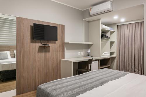 a bedroom with a bed and a desk with a television at Valerim Florianópolis in Florianópolis