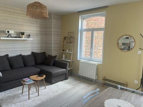 a living room with a black couch and a table at Les Bêtises, Duplex Hyper-centre in Cambrai