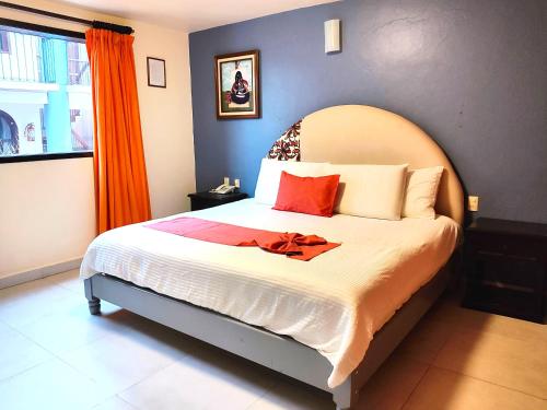 a bedroom with a large bed with an orange curtain at Hotel Jardines Del Carmen in San Cristóbal de Las Casas