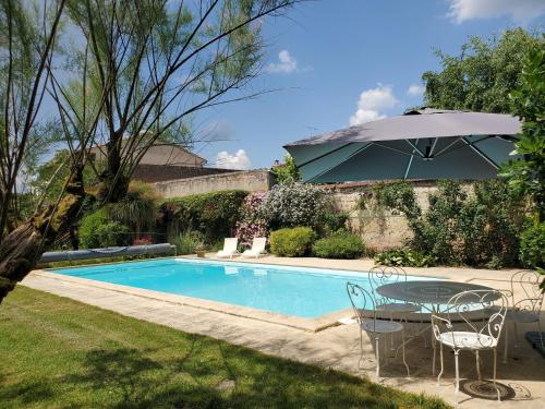 - une table avec un parasol à côté de la piscine dans l'établissement La Villa du Portail, à Le Passage