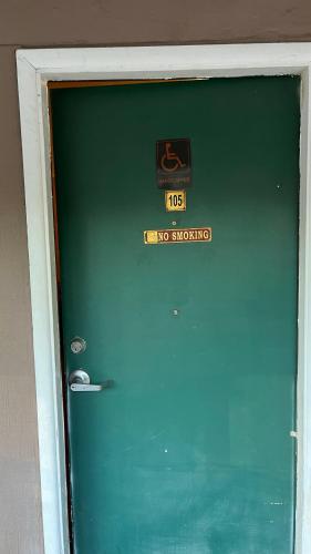 a green door with a no smoking sign on it at Jumping Frog Motel in Angels Camp