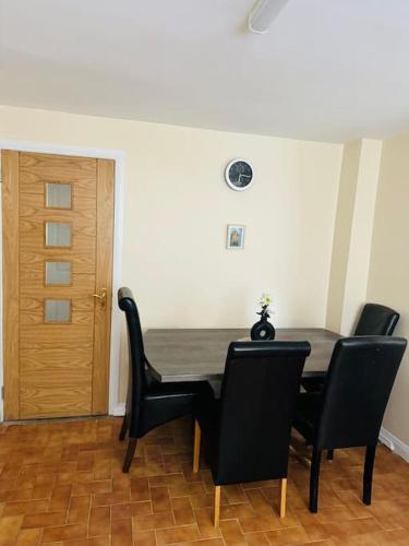 a dining room with a table and black chairs at Willow Haven in Ballykelly