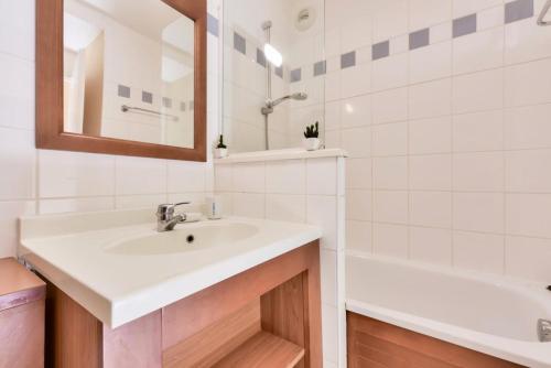 une salle de bain avec un lavabo, une baignoire et un miroir dans l'établissement Résidence Les Grands Pins - maeva Home - Appartement 2 pièces 4 personnes - Sélection MAE-7914, à Maubuisson