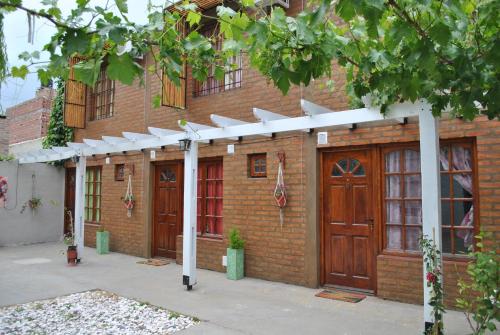 a brick building with wooden doors and a white pergola at Departamentos Betania in Las Grutas