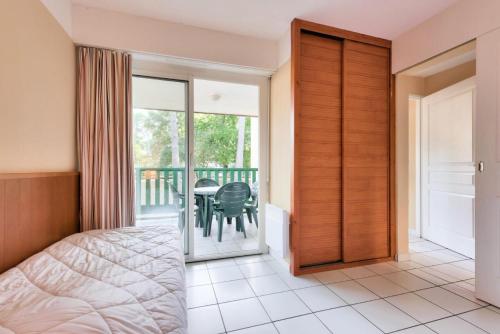 a bedroom with a bed and a balcony with a table at Résidence Les Grands Pins - maeva Home - Appartement 2 pièces 4 personnes - Sélection MAE-3004 in Maubuisson