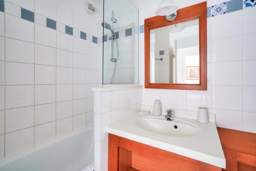 une salle de bain avec un lavabo, un miroir et une baignoire dans l'établissement Résidence Les Grands Pins - maeva Home - Appartement 2 pièces 5 personnes - Prestige MAE-3024, à Maubuisson