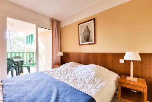 a bedroom with a bed and a balcony with a table at Résidence Les Grands Pins - maeva Home - Appartement 2 pièces 5 personnes - Confort MAE-0384 in Maubuisson