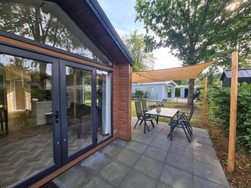 a patio with a table and chairs and a tent at Modern chalet met ruimte tuin op de Veluwe in Epe