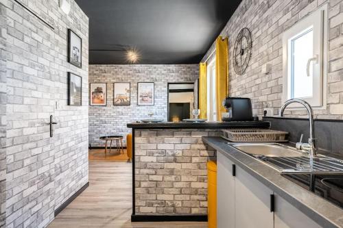 - une cuisine avec un évier et un mur en briques dans l'établissement La Factory, de Bergerac !, à Bergerac
