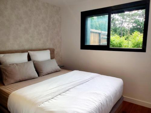 une chambre avec un lit blanc avec une fenêtre dans l'établissement Au calme du Golf - Appartement Chic 5 étoiles, à Hossegor