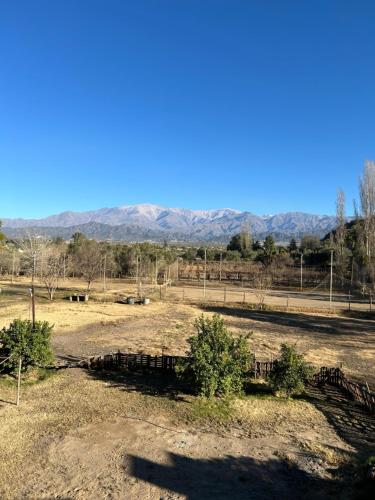a field with trees and mountains in the background at Cabañas Balcón del Famatina in Chilecito