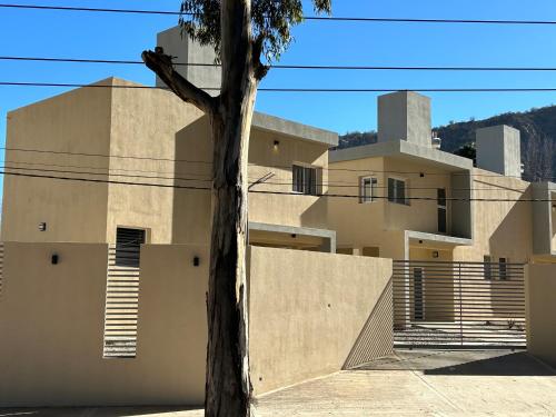 a building with a tree in front of it at Cabañas Balcón del Famatina in Chilecito