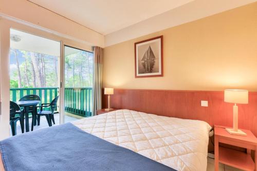 a bedroom with a bed and a balcony at Résidence Les Grands Pins - maeva Home - Appartement 2 pièces 5 personnes - Sélection MAE-2171 in Maubuisson