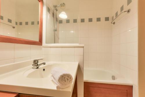 a white bathroom with a sink and a tub at Résidence Les Grands Pins - maeva Home - Appartement 2 pièces 5 personnes - Sélection MAE-2171 in Maubuisson