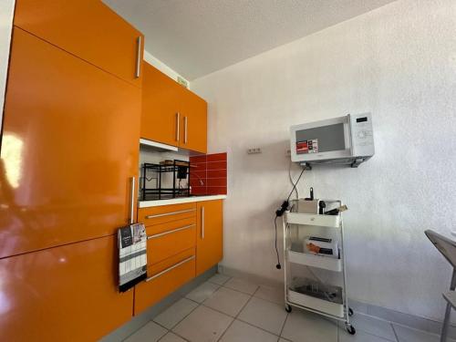 - une cuisine avec des armoires orange et un four micro-ondes dans l'établissement Grand studio proche plages, à La Londe-les-Maures