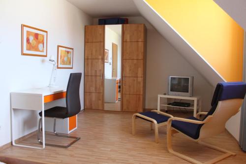 een woonkamer met een bureau en stoelen en een trap bij Reethaus Deichkrone in Breege