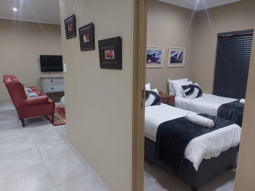 a hotel room with two beds and a chair at Lloyds - 9 in Ermelo