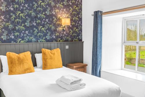 a bedroom with a bed with yellow pillows and a wallpaper at The Redwell Country Inn in Arkholme