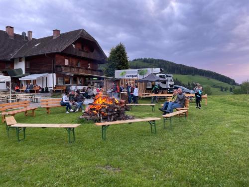 un grupo de personas sentadas alrededor de un fuego delante de un edificio en Gruppenhaus Hirzhof, en Auberg