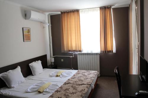 a hotel room with two beds and a window at Guest House Lazur in Burgas