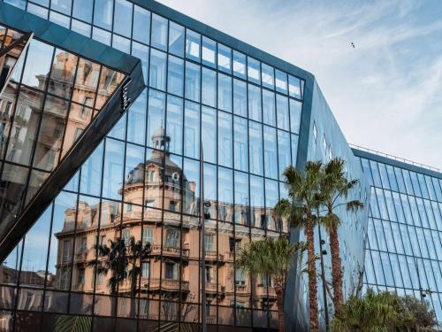 un vieux bâtiment se reflétant dans la vitre d'un bâtiment dans l'établissement Doubletree By Hilton Nice Centre Iconic, à Nice