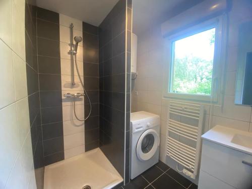 une salle de bain avec douche et machine à laver dans l'établissement La petite maison dans la prairie, à Plouay