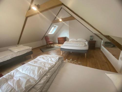Cette chambre mansardée comprend deux lits et une chaise. dans l'établissement La petite maison dans la prairie, à Plouay