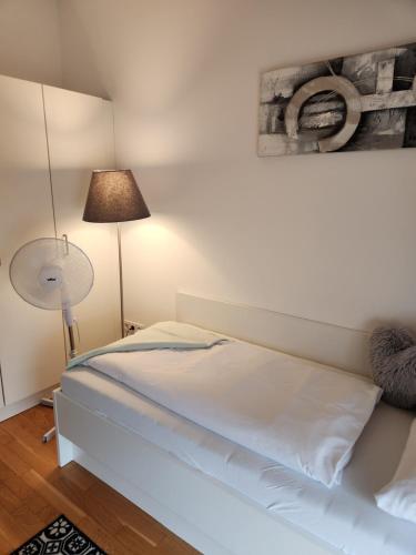 ミュンヘンにあるMyRoom - Munich Fair Apartmentsの白いベッドとランプのある寝室