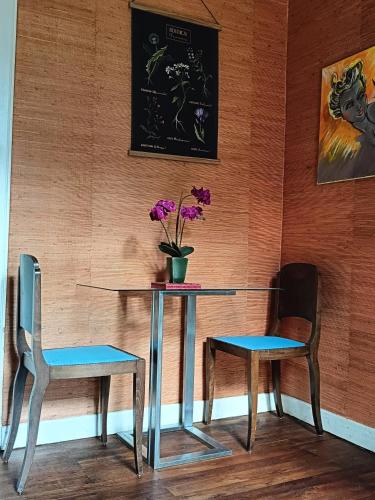 une table, deux chaises et un vase avec des fleurs dans l'établissement Les chambres des artistes, à Laguépie