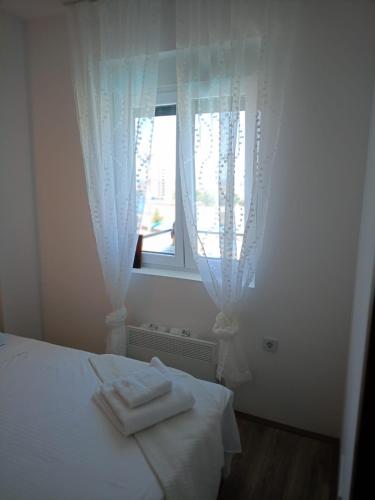 a bedroom with a bed with white sheets and a window at Jagodina Apartman Nastasija- gleda na Aqva park in Jagodina