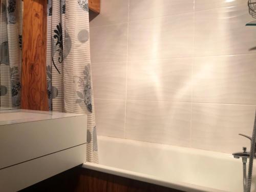 La salle de bains est pourvue d'une baignoire et d'un rideau de douche. dans l'établissement Résidence Le Chardonnet - Studio à deux pas du centre station MAE-9164, à Aime La Plagne